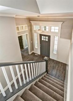 Entryway with gray stair rail and white ballusters. Crystal entry chandelier. Tuftex carpet with Manningtons Restoration Collection laminate flooring in Black Forest Oak fumed. Benjamin Moore Kendal Charcoal front door with White Dove trim. Transom windows above door frames.
