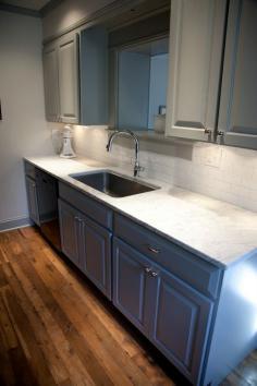 Kitchen Cabinets painted in Benjamin Moore Fieldstone. Restoration Hardware Satin Nickel Pulls. Oak flooring. Carrera Marble Countertop. Essenze Ice Subway Tile. F