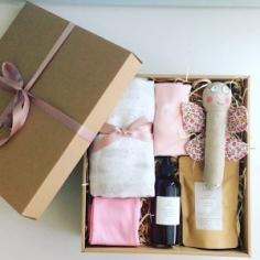 Baby Box in Pinks contains a number of baby items including clothing, a wrap, a rattle and some bath products gift wrapped in a craft box - ...